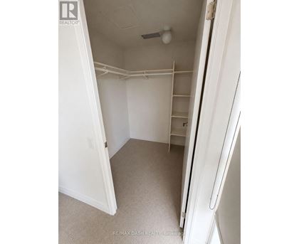 A white bedroom with a door open to a hallway.