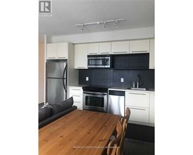 A kitchen with white cabinets and black countertops.