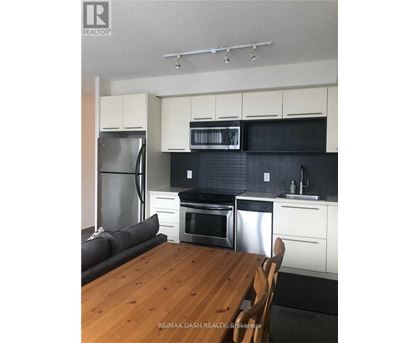 A kitchen with white cabinets and black countertops.