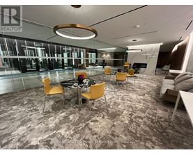 A modern office space with a glass wall and a round table with yellow chairs.