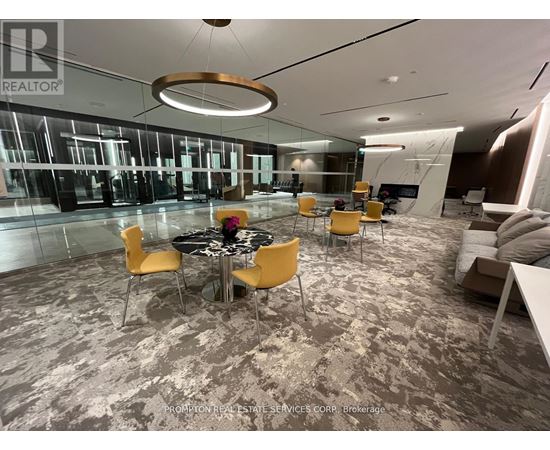 A modern office space with a glass wall and a round table with yellow chairs.