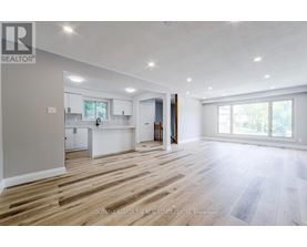 A spacious, empty room with wooden flooring and white walls.