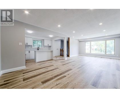 A spacious, empty room with wooden flooring and white walls.
