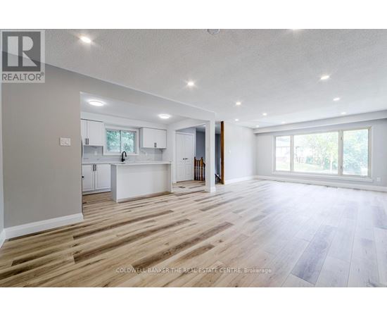 A spacious, empty room with wooden flooring and white walls.