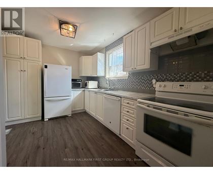 A kitchen with white appliances and wooden floors.