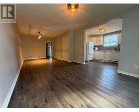 A spacious room with wooden floors and a large window.