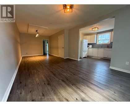 A spacious room with wooden floors and a large window.