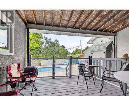 A patio with a table, chairs, and a pool in the background.