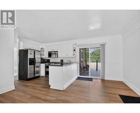 A kitchen with white cabinets and a black fridge.