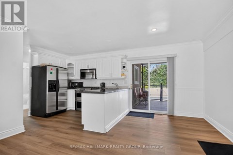 A kitchen with white cabinets and a black fridge.