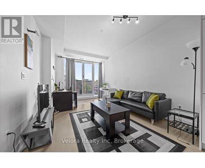 A modern living room with a grey sofa and a black and white rug.