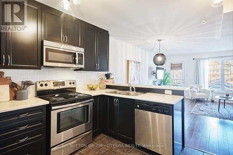 A modern kitchen with black cabinets and stainless steel appliances.