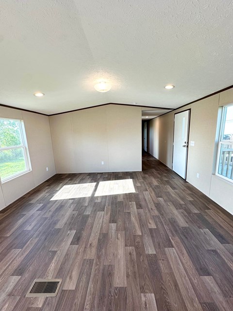 A room with wooden flooring and a window on the left side.