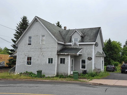 A grey house with a sign on the front.
