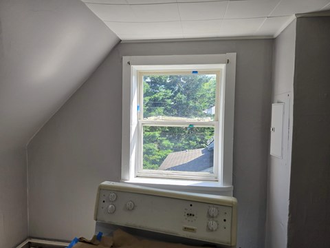 A window in a room with a view of a driveway and trees.