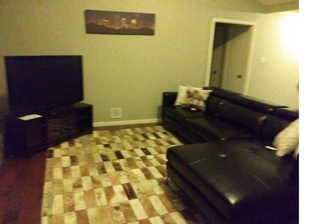 A black couch with a checkered floor in front of it.