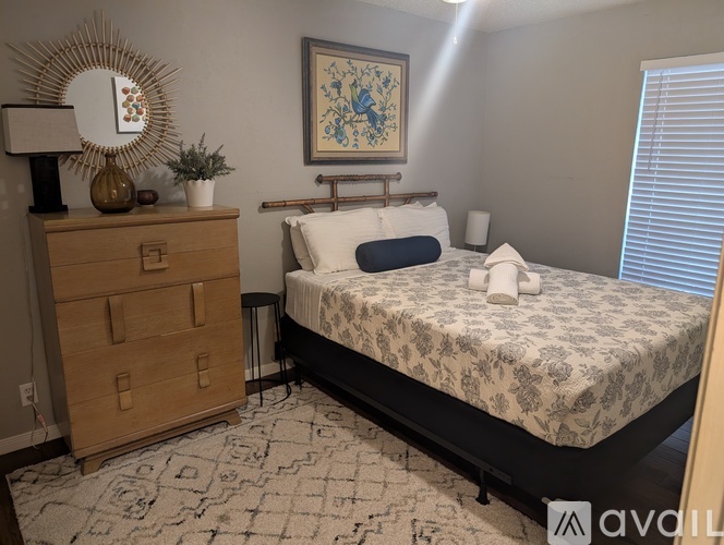 A bedroom with a bed, dresser, and a painting on the wall.