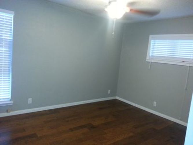 A room with a ceiling fan and wooden floors.