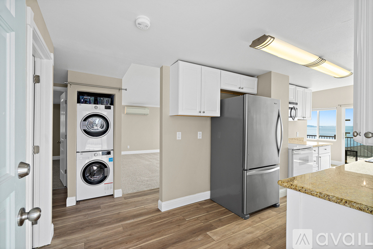 A kitchen with a refrigerator, dishwasher, and washer/dryer combo unit.