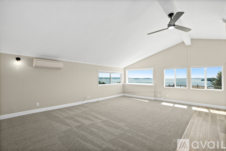 A spacious room with a ceiling fan and large windows overlooking the water.