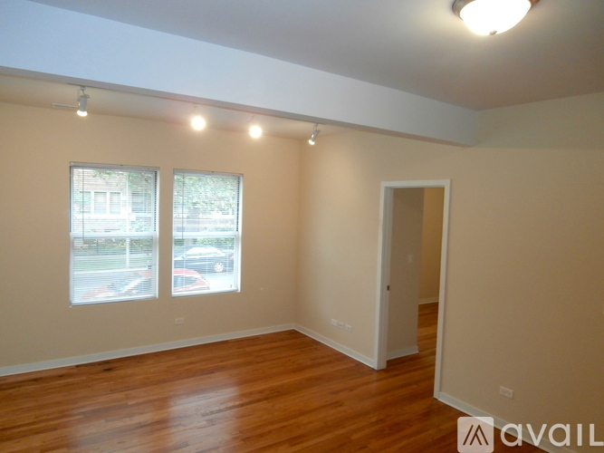Empty room with wooden floor and two windows.