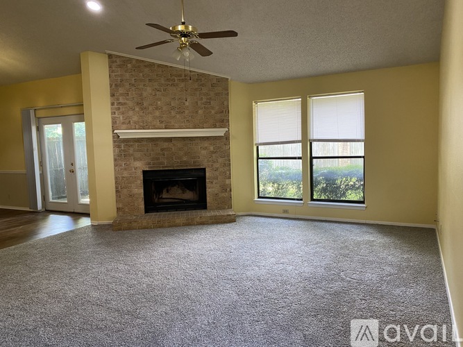 A living room with a fireplace and a ceiling fan.