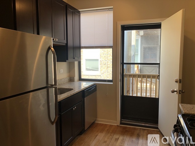 A kitchen with a stainless steel refrigerator and black cabinets.