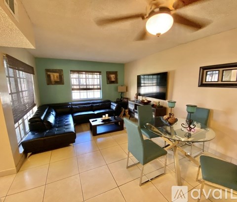 A living room with a black leather couch and a glass dining table.