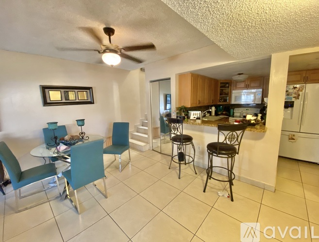 A kitchen with a table and chairs in the foreground and a refrigerator in the background.