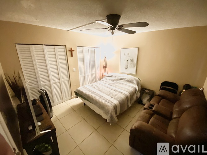 A bedroom with a bed, a couch, and a ceiling fan.