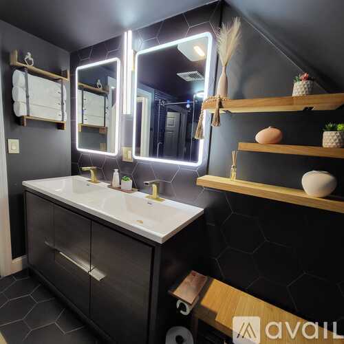 A bathroom with a vanity, mirrors, and shelves.