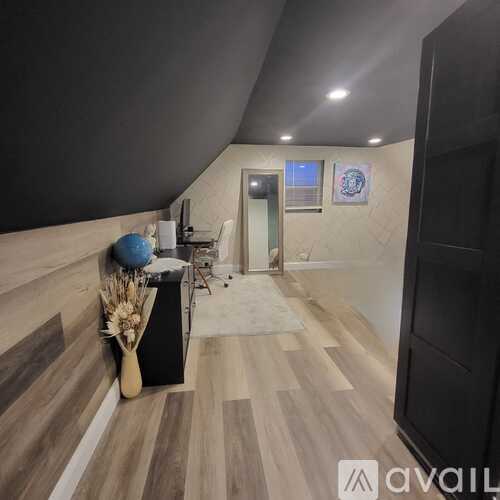 A hallway with a black door and a white door, a vase with flowers and a blue ball on a table.