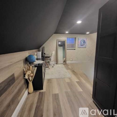 A hallway with a black door and a white door, a vase with flowers and a blue ball on a table.