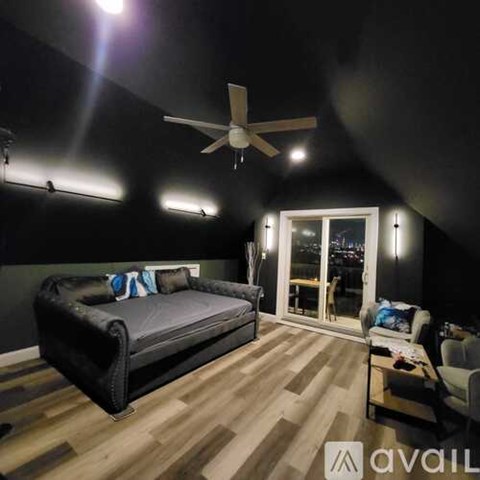 A modern living room with a black sofa and a ceiling fan.