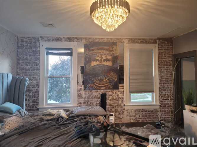 A bedroom with a brick wall and a large painting hanging above the bed.