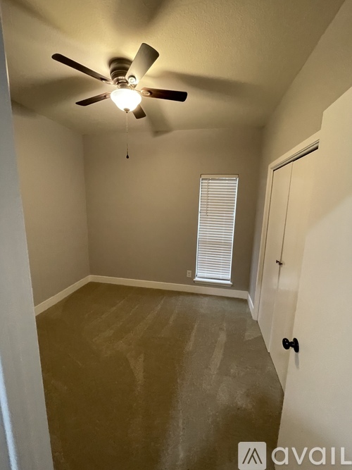 A room with a ceiling fan and a window with blinds.