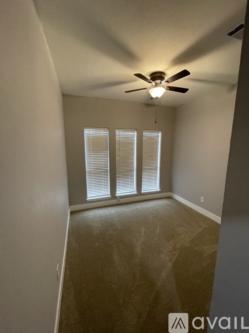 A room with a ceiling fan and a window with blinds.