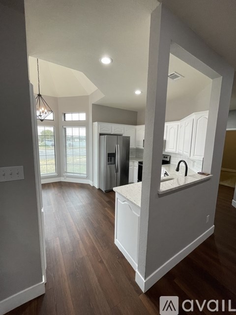 A kitchen with white cabinets and a wooden floor.