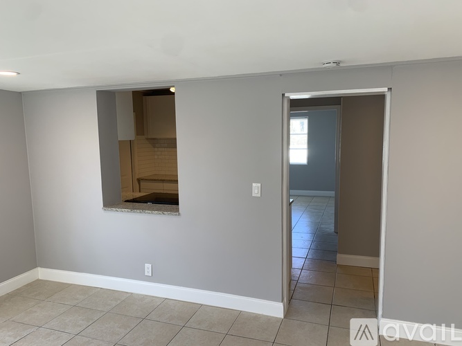 A room with a doorway leading to another room and a mirror on the wall.