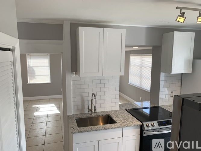 A kitchen with white cabinets and a black stove top oven.