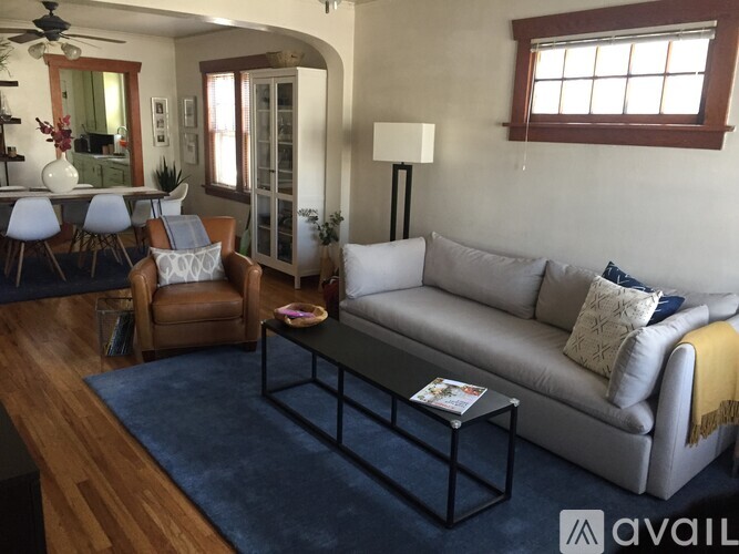 A living room with a grey couch, a brown chair, and a blue rug.