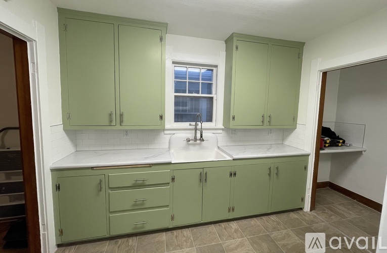 A kitchen with green cabinets and a window.