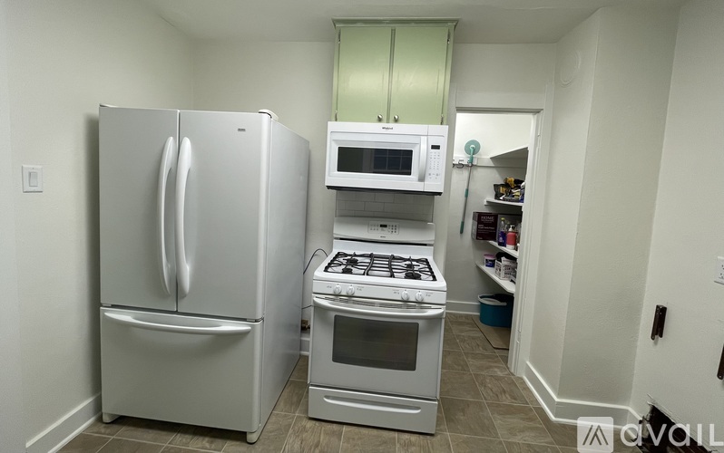 A kitchen with a stainless steel refrigerator, a white oven, and a white microwave.