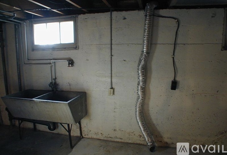 A room with a window, a sink, and a metal container.