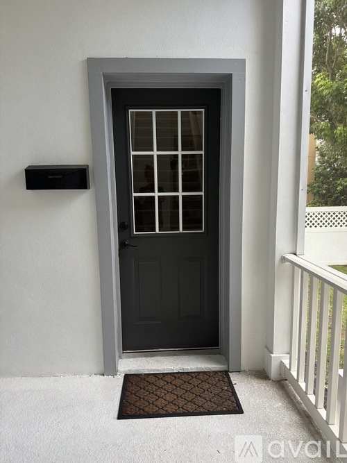 A black door with a window in the middle and a mailbox on the wall.
