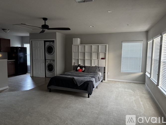 A bedroom with a bed, a ceiling fan, and a washing machine.