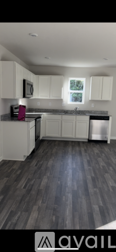 A kitchen with white cabinets and a wooden floor.