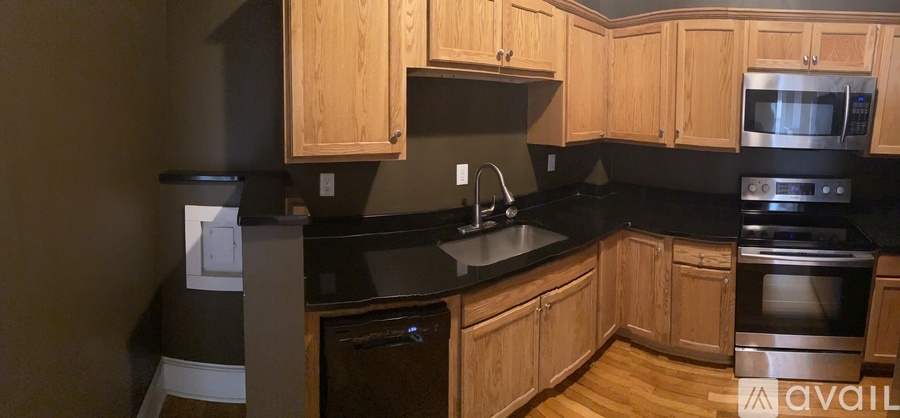 A kitchen with wooden cabinets and black countertops.