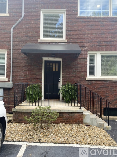 A brick house with a black door and a small front yard.