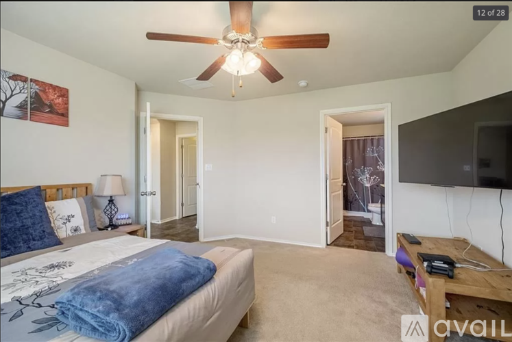 A bedroom with a large bed and a ceiling fan.